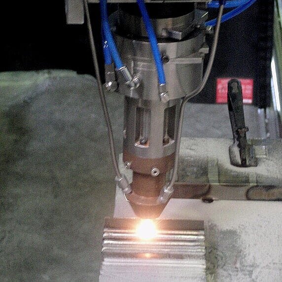 Laserauftragsschweißen (Cladding) auf einer Metalloberfläche mit industriellem Bearbeitungskopf
