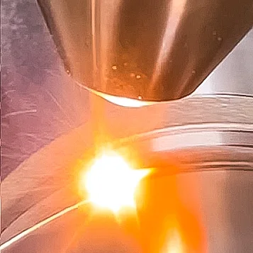 Laserauftragsschweißen (Cladding) mit Bearbeitungskopf auf einem Metallbauteil